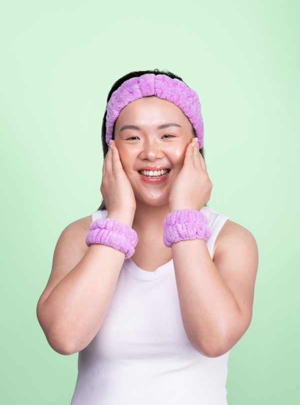 Girl wearing purple skincare headband in turban style and matching purple spa wristbands