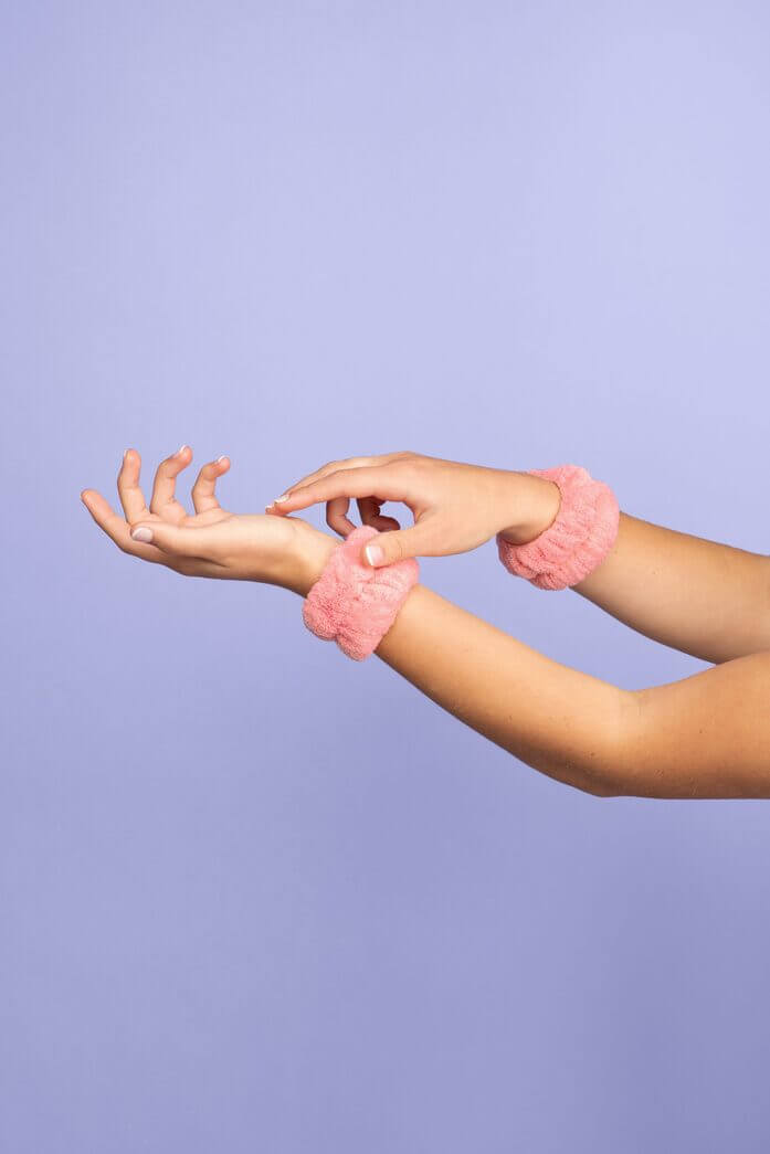 Pair of pink face washing wrist towels shown on female wrist