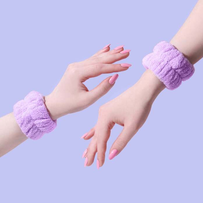 Pair of purple face washing wrist towels shown on female wrists