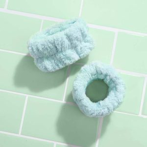 Pair of green mint face washing wrist towels on green bathroom tiles