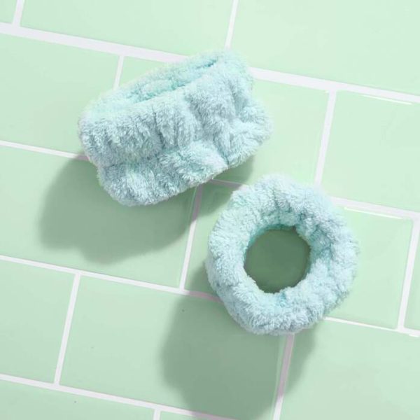 Pair of green mint face washing wrist towels on green bathroom tiles